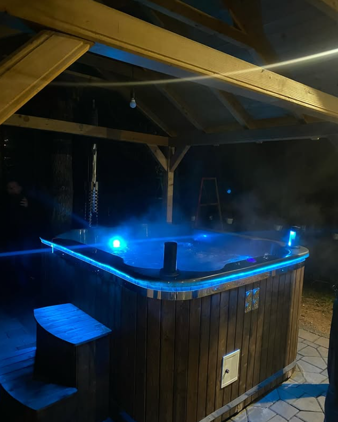 Hot tub with blue LED lighting at night under wooden gazebo